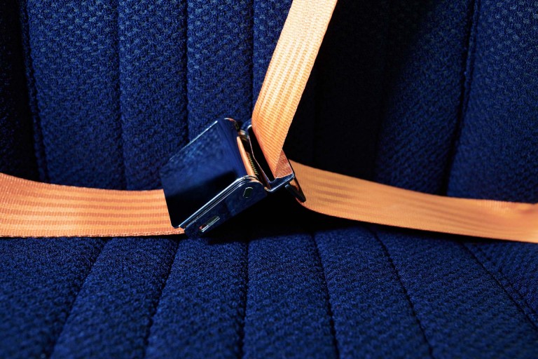 Close-up of the orange seatbelts in contrast to the elegant dark blue seats. 